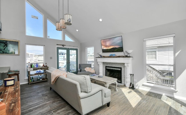 living room featuring french doors, a tiled fireplace, hardwood / wood-style flooring, an inviting chandelier, and high vaulted ceiling