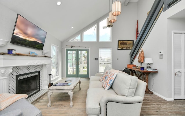 living room featuring french doors, high vaulted ceiling, wood-type flooring, and a tile fireplace