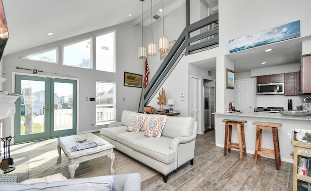 living room with french doors, light hardwood / wood-style flooring, and high vaulted ceiling