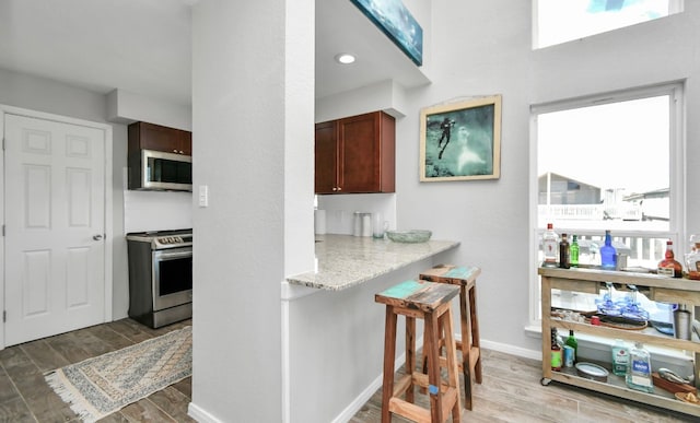 kitchen featuring hardwood / wood-style floors, light stone countertops, and stainless steel appliances