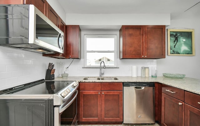 kitchen with stainless steel appliances, sink, light stone counters, and backsplash