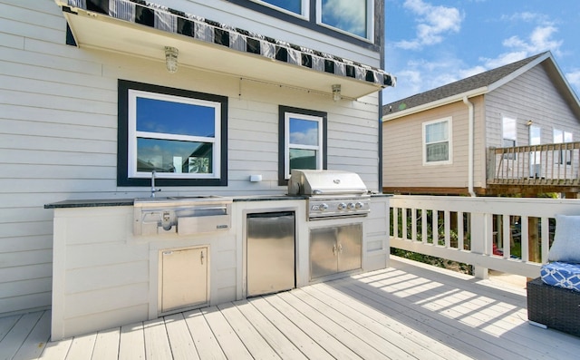 wooden deck with area for grilling and an outdoor kitchen