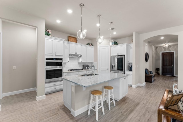 kitchen featuring white cabinetry, light stone countertops, an island with sink, and appliances with stainless steel finishes