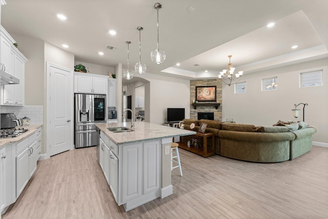 kitchen featuring white cabinets, stainless steel fridge with ice dispenser, and an island with sink