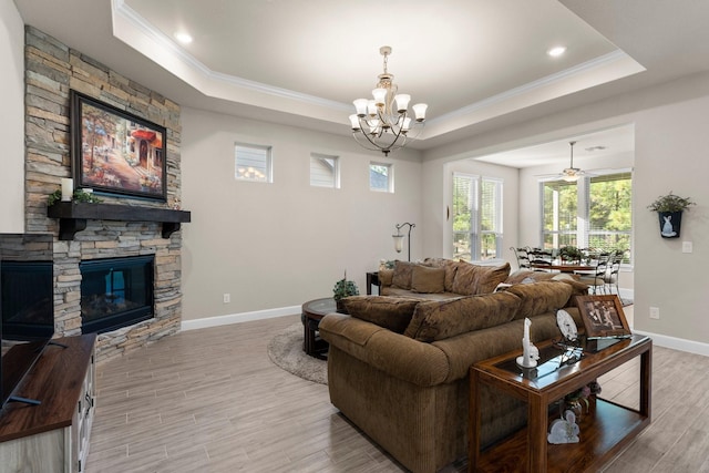 living room with ceiling fan with notable chandelier, a raised ceiling, hardwood / wood-style flooring, ornamental molding, and a fireplace