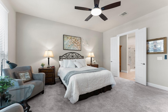 bedroom with connected bathroom, light colored carpet, multiple windows, and ceiling fan