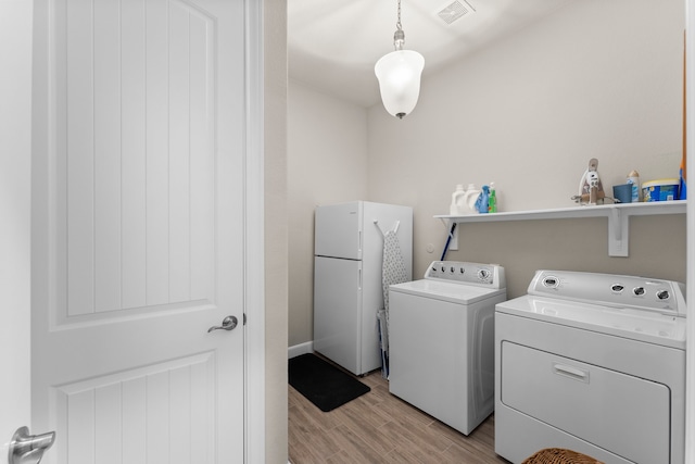 clothes washing area featuring washer and dryer and light hardwood / wood-style floors