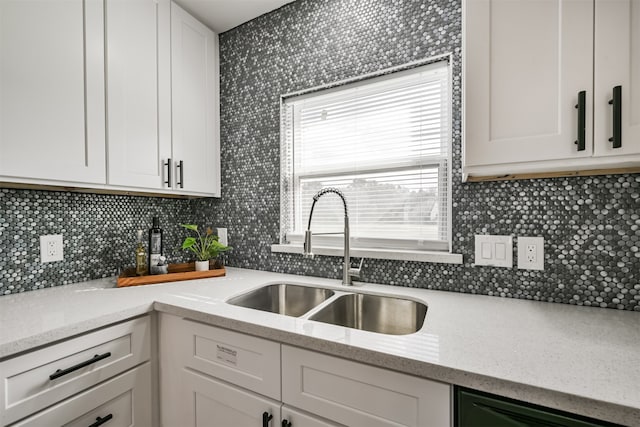 kitchen with decorative backsplash, black dishwasher, white cabinetry, and sink