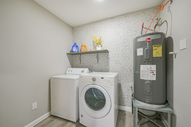 clothes washing area with independent washer and dryer, light hardwood / wood-style flooring, and water heater