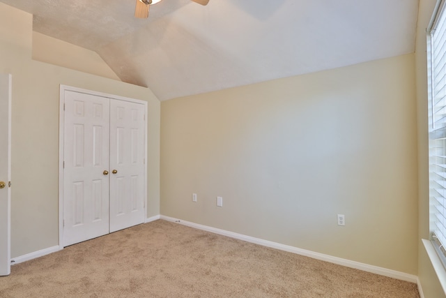 unfurnished bedroom featuring a closet, ceiling fan, light carpet, and lofted ceiling