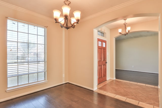 foyer with ornamental molding, a notable chandelier, and hardwood / wood-style flooring