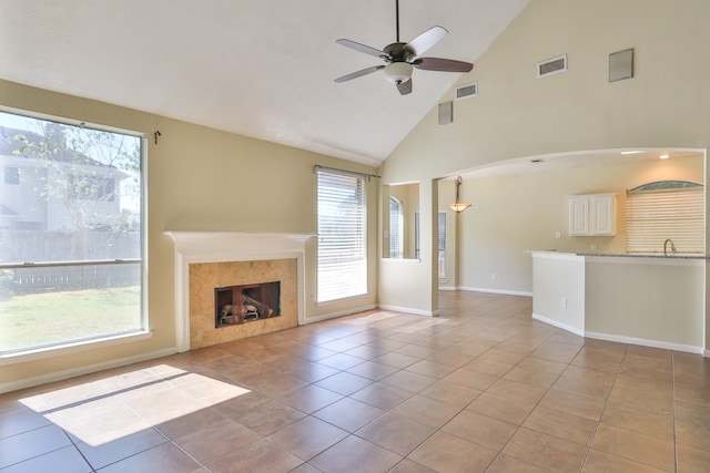 unfurnished living room featuring high vaulted ceiling, a healthy amount of sunlight, light tile patterned floors, and a fireplace