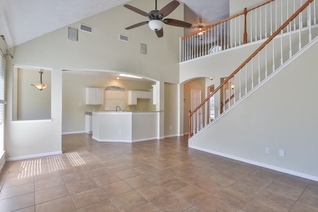 unfurnished living room featuring tile patterned flooring, high vaulted ceiling, and ceiling fan