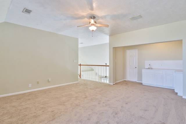 carpeted empty room with a textured ceiling, vaulted ceiling, and ceiling fan