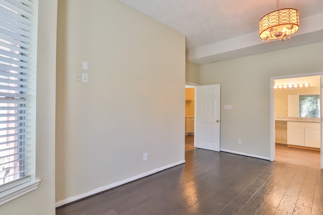 unfurnished room with dark wood-type flooring and a notable chandelier