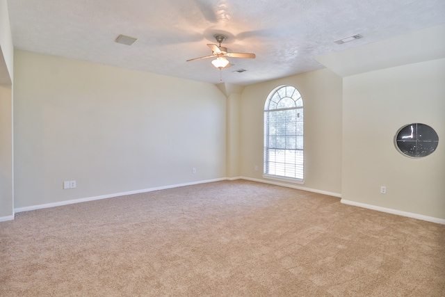 carpeted spare room with a textured ceiling and ceiling fan