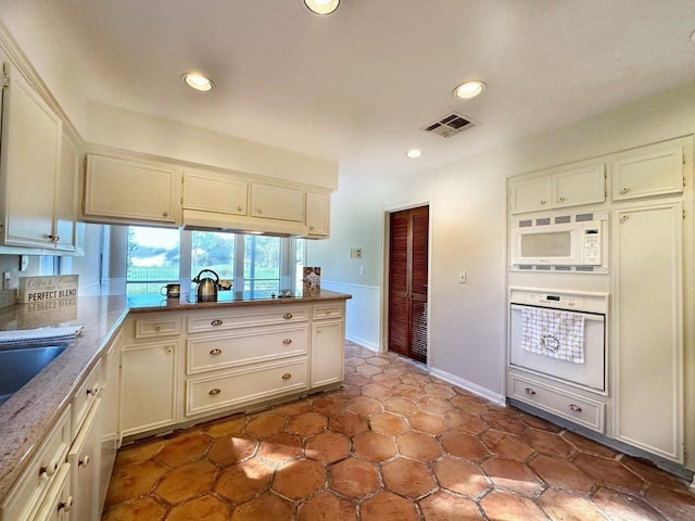 kitchen featuring kitchen peninsula, light stone countertops, and white appliances