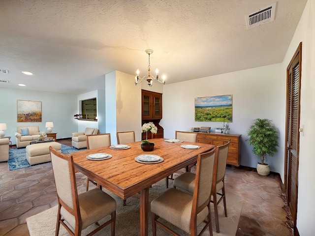 dining space with a textured ceiling and a notable chandelier