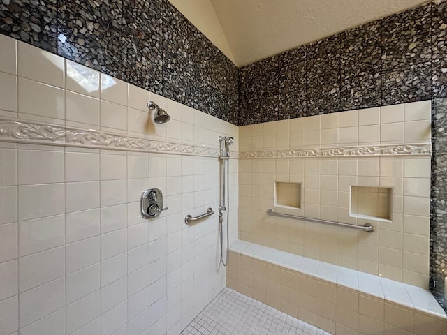 bathroom with tile patterned floors, a tile shower, and vaulted ceiling