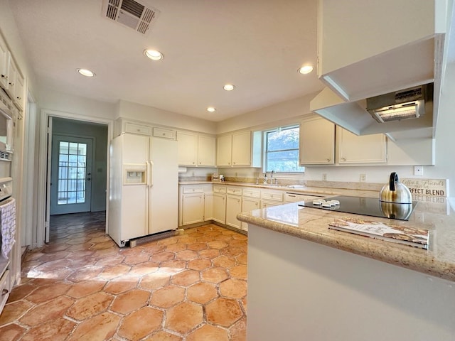 kitchen featuring white fridge with ice dispenser, sink, light stone counters, black electric cooktop, and white cabinets