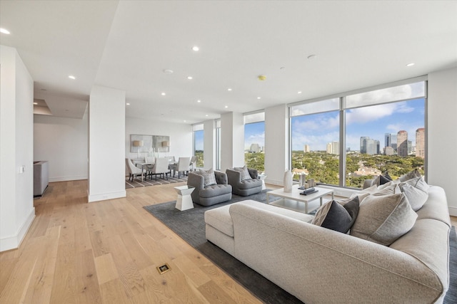 living area featuring light wood-style floors, recessed lighting, baseboards, and a city view