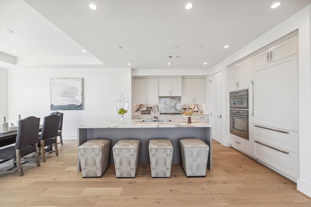 kitchen featuring light hardwood / wood-style floors, sink, and an island with sink