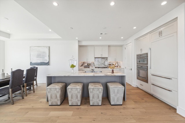 kitchen featuring a sink, light stone countertops, recessed lighting, and visible vents