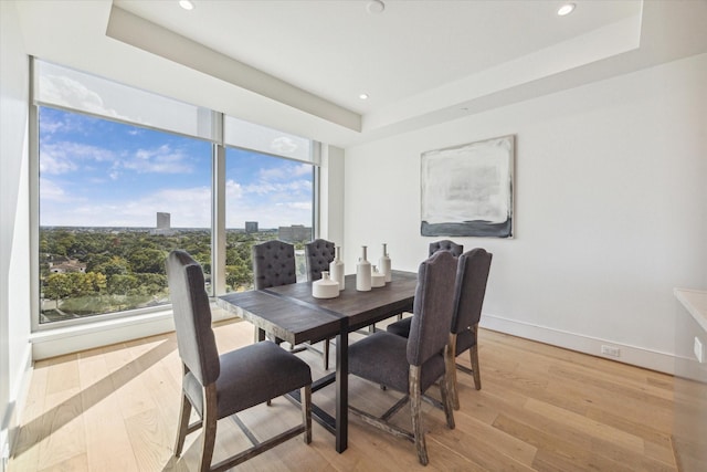 dining space with recessed lighting, a tray ceiling, and light wood finished floors