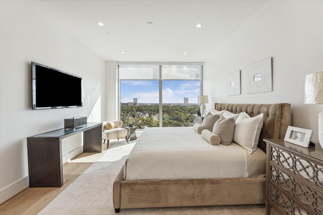 bedroom with expansive windows, recessed lighting, light wood finished floors, and baseboards