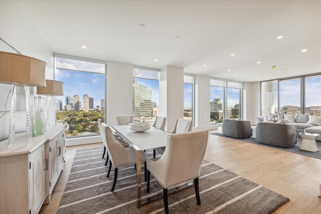 dining area with recessed lighting, a city view, light wood-style flooring, and a healthy amount of sunlight