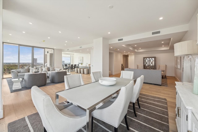 dining space with light hardwood / wood-style floors and a tray ceiling