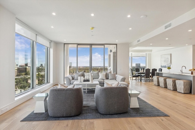 living room with recessed lighting, light wood finished floors, and visible vents