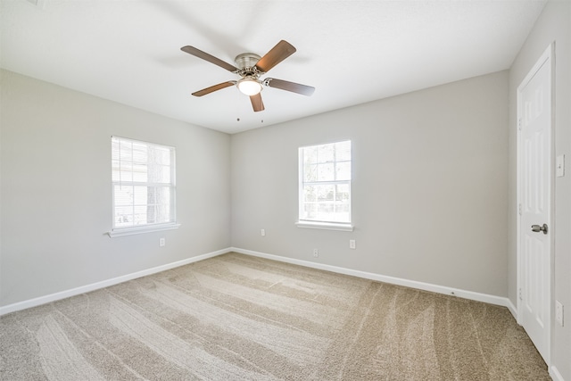 empty room with a wealth of natural light, carpet, and ceiling fan