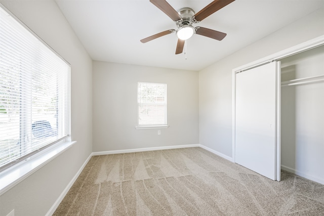 unfurnished bedroom with light carpet, multiple windows, a closet, and ceiling fan