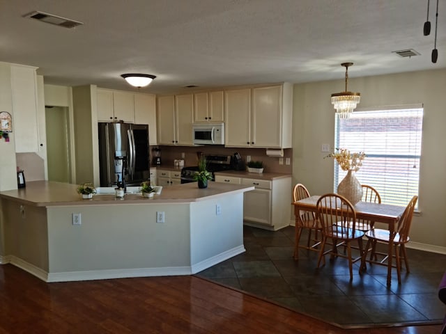 19626 Tularosa Ln, Tomball, TX 77377 - kitchen with white microwave, gas range oven, stainless steel refrigerator with ice dispenser, a chandelier, and a peninsula