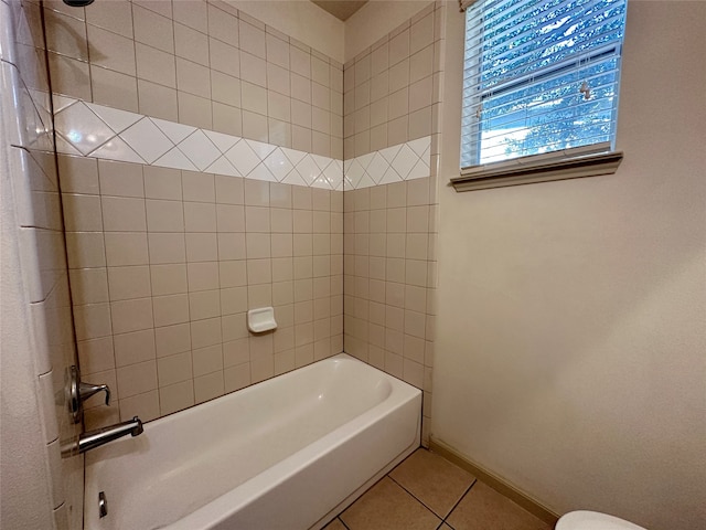 bathroom featuring tiled shower / bath combo, toilet, and tile patterned flooring