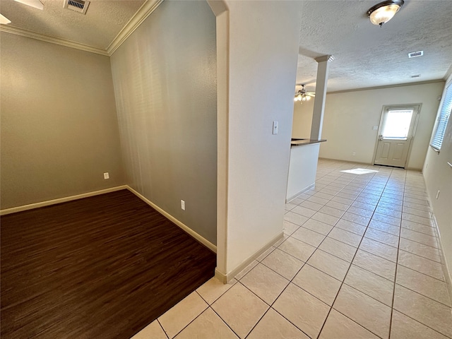 spare room with crown molding, a textured ceiling, light wood-type flooring, and ceiling fan