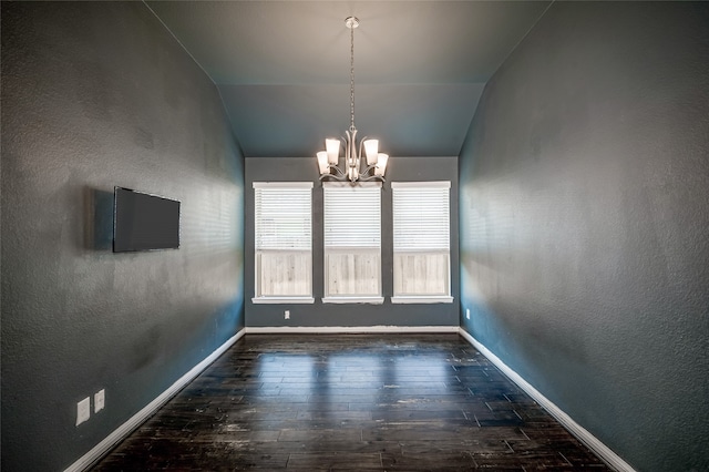 unfurnished dining area featuring dark hardwood / wood-style flooring, a chandelier, and vaulted ceiling