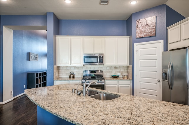 kitchen featuring appliances with stainless steel finishes, white cabinets, tasteful backsplash, and light stone counters