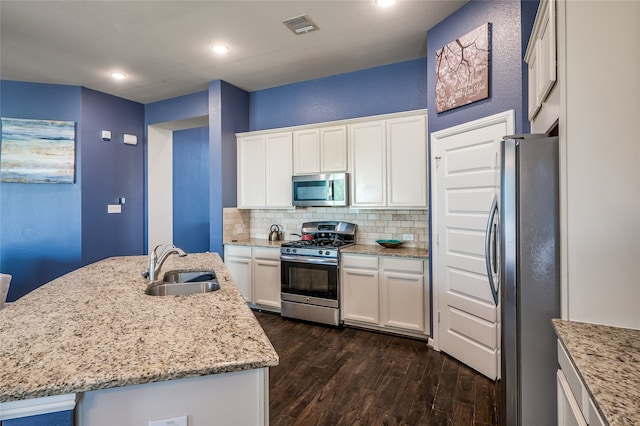 kitchen featuring a kitchen island with sink, dark wood-type flooring, stainless steel appliances, sink, and white cabinets