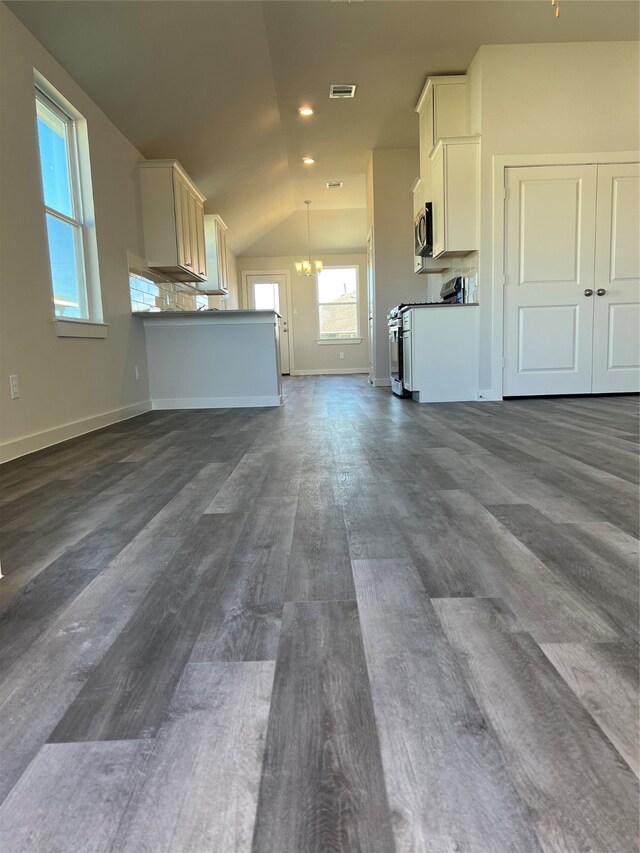 unfurnished living room featuring dark hardwood / wood-style floors, a chandelier, and vaulted ceiling