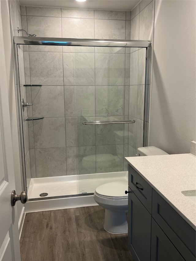 bathroom featuring toilet, hardwood / wood-style flooring, walk in shower, and vanity