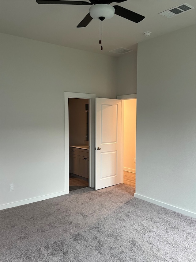 unfurnished bedroom featuring light carpet, ensuite bathroom, and ceiling fan