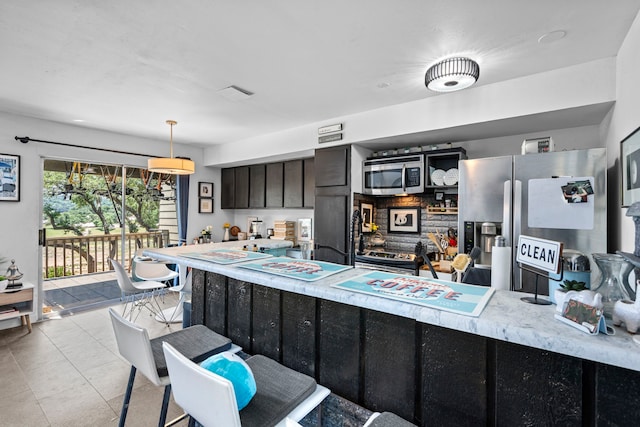 kitchen with stainless steel appliances, dark brown cabinets, light tile patterned flooring, and hanging light fixtures