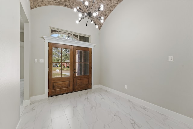 foyer entrance with french doors, high vaulted ceiling, and a notable chandelier