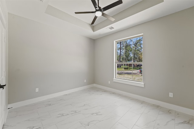 unfurnished room with ceiling fan and a raised ceiling