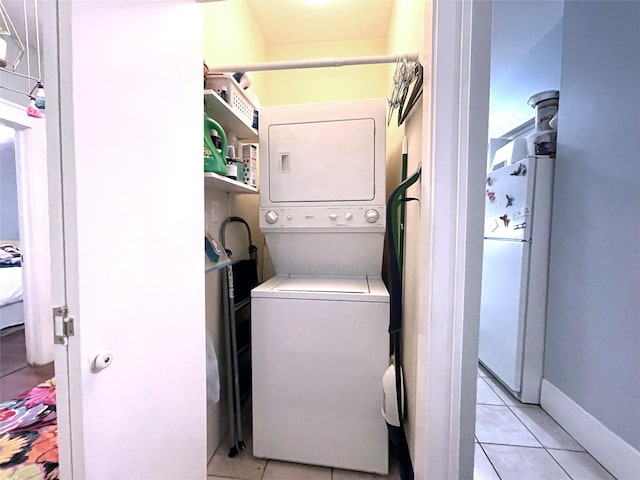 laundry area with stacked washing maching and dryer and light tile patterned flooring