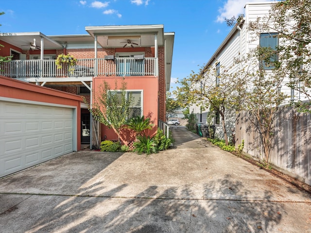 view of front of property featuring a garage, ceiling fan, and a balcony