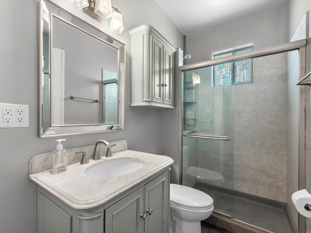 bathroom with toilet, vanity, and a shower with shower door