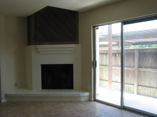 unfurnished living room with a brick fireplace, a textured ceiling, and light tile patterned floors